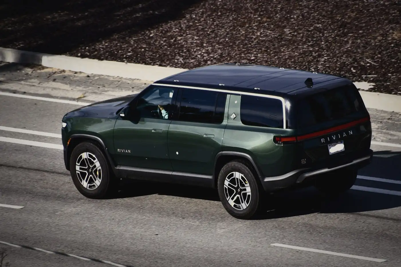 Rivian R1S in a deep green finish on the road, seen from above