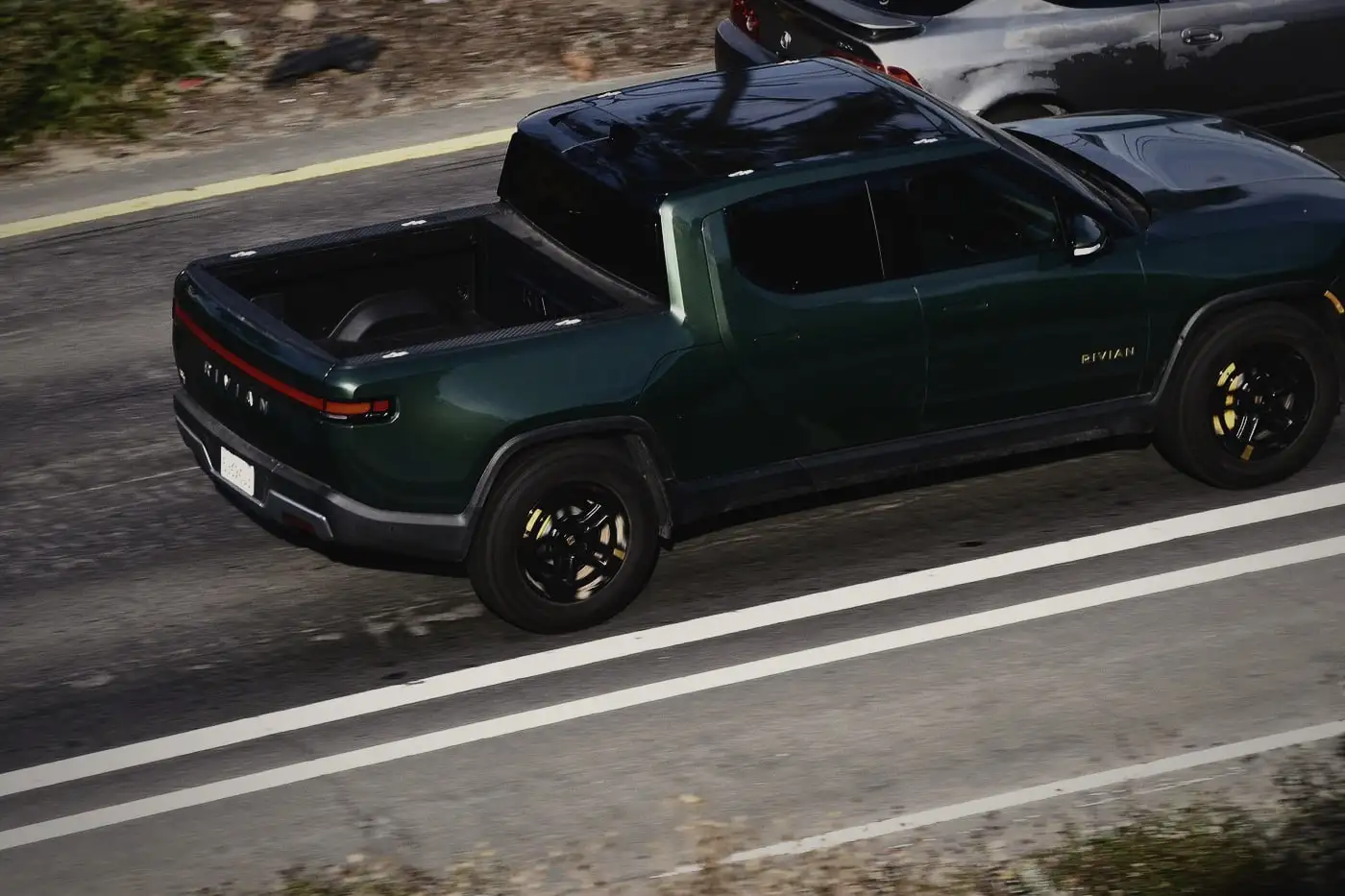 Rivian R1T in a deep green finish on the road, seen from above
