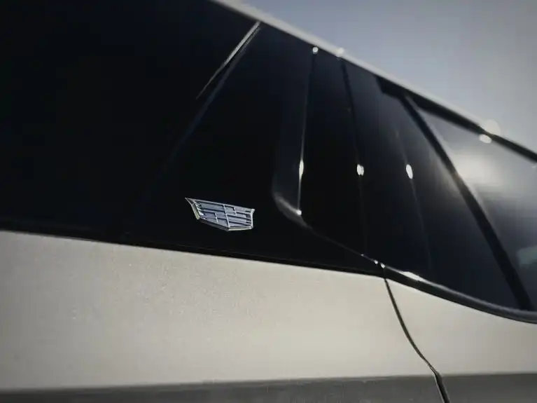 Dark window tint on the rear glass of a silver Cadillac Escalade