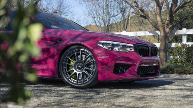 BMW M5 Fuchsia Pink Vinyl Wrap Front Quarter Wheel Yellow Brake Caliper Foliage Foreground, by Wrap Labs, Westlake Village