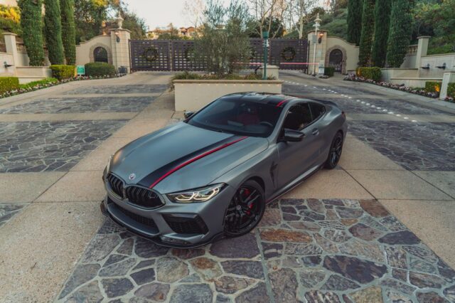 BMW M8 Competition Matte Grey Black Red Stripe Vinyl Wrap Front 3Quarter Estate Gate, by Wrap Labs, Westlake Village